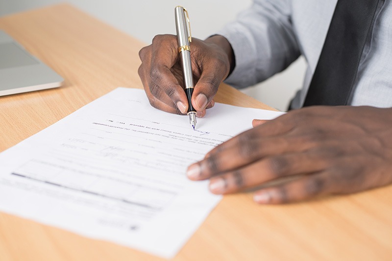 close up of a man's hands signing a document
